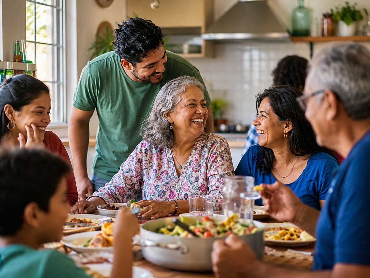 Familia sudamericana multigeneracional riendo juntos alrededor de la mesa del comedor en casa